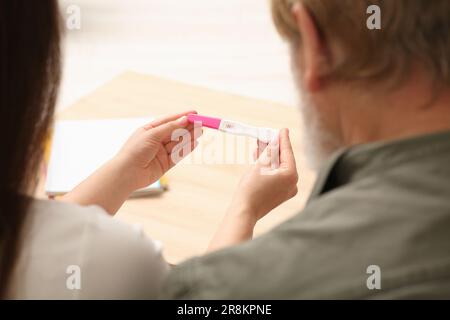 Figlia che mostra il suo padre prova di gravidanza al chiuso, primo piano. Reazione dei nonni al futuro nipote Foto Stock