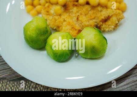 Lenticchie e cavoletti di bruxelles bolliti verdi su un piatto bianco Foto Stock