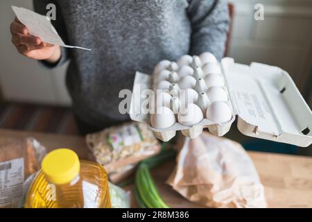 Donna che verifica la ricezione dal supermercato durante l'inflazione con l'aumento dei prezzi dei prodotti alimentari e di consumo Foto Stock