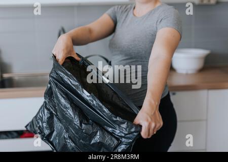 Sezione centrale della donna che tiene il sacco della spazzatura Foto Stock