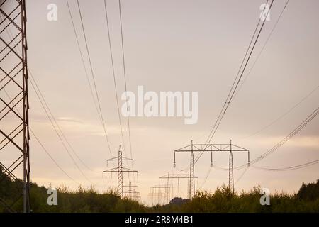 Vista angolare bassa dei tralicci elettrici contro il cielo serale Foto Stock