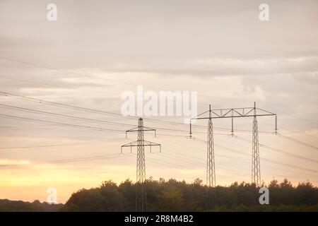 Vista angolare bassa dei tralicci elettrici contro il cielo serale Foto Stock