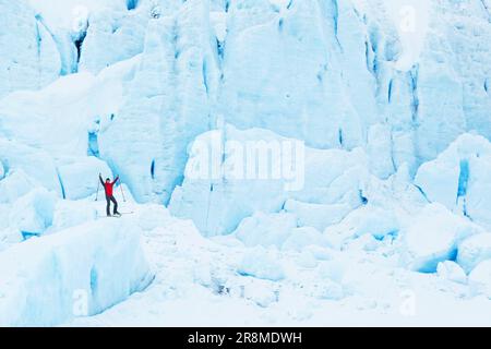 Un uomo che sale su una montagna coperta di grandi ciance bianche di neve Foto Stock