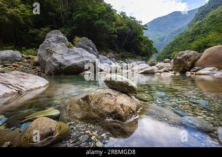 Foto idilliaca di un ruscello che scorre attraverso la valle del Parco Nazionale di Taroko. L'acqua setosa cade su grandi pietre, creando una scena serena. Allo Shak Foto Stock