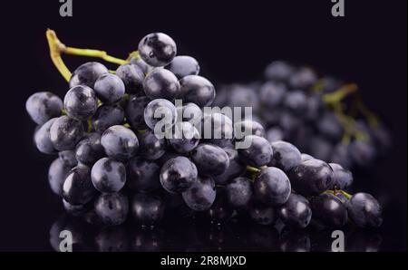 Mazzetto di maturi uva scuro isolati su sfondo nero Foto Stock