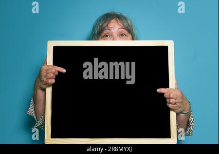 Donna anziana dai capelli bianchi che tiene una lavagna con spazio per copiare il testo Foto Stock