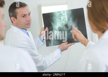 Medico che mostra raggi X dell'area pelvica Foto Stock