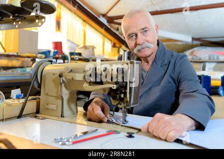 Meccanico senior di riparazione di macchina per cucire industriale in fabbrica Foto Stock