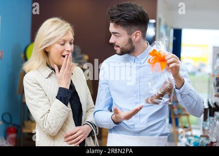 donna bionda felice che compra il cioccolato nel negozio di caramelle Foto Stock