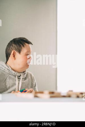 Anziana donna con sindrome di Down a casa gioca nella torre da blocchi di legno Foto Stock