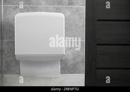 Nuovo dispenser di asciugamani di carta appeso alla parete del bagno Foto Stock