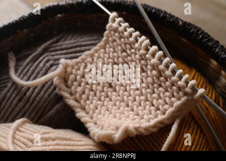 Morbidi fili colorati, maglieria e aghi metallici su tavola di legno, primo piano Foto Stock