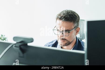 Lavoro remoto e concattività modrn. Incontro virtuale con molti partecipanti online. Webinar. Uomo d'affari che parla online con i dipendenti tramite connessione video Foto Stock