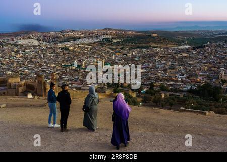 Marocco. Fez. Persone sulla collina sopra la vecchia medina a Fez al crepuscolo. Al centro la moschea Karaouiyine Foto Stock