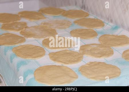 Molti pezzi di pasta arrotolata per torte su un tovagliolo sul tavolo in cucina Foto Stock