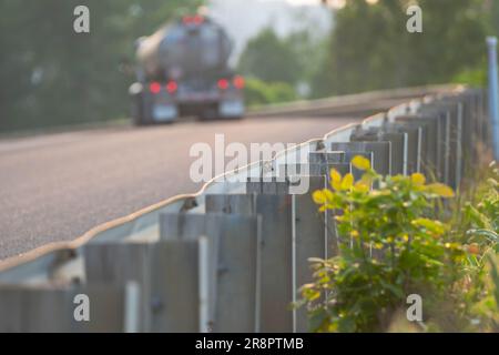 recinzione a bordo strada con sfondo sfocato del passaggio dei camion di carburante, risorse grafiche sfondi per il trasporto di risorse in luce naturale Foto Stock