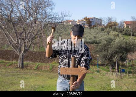 Immagine di un uomo che guida un paletto con una freccia nel terreno con un martello. Palo indicante la direzione da seguire. Foto Stock