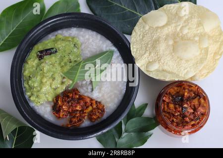 Kanji e Kadumanga. Gruel di riso preparato con riso Kerala Matta. Servita in pentola di terracotta con posate di foglie di jackpot. Shot con sottaceti al mango tagliati, crudi Foto Stock