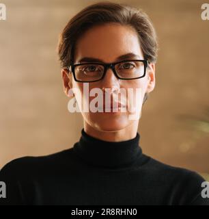 Primo piano ritratto di una donna d'affari fiduciosa con capelli corti indossando occhiali guardando direttamente in una macchina fotografica Foto Stock