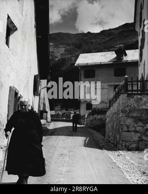 Pontresina -- la vita nelle alte Alpi della Svizzera. Mountain Street: Una vecchia signora scende lungo la ripida pendenza della strada che conduce ad Alp LANguard. Questa è la parte più antica di Pontresina. Gennaio 22, 1948. (Foto di Foto stampa pittorica). Foto Stock