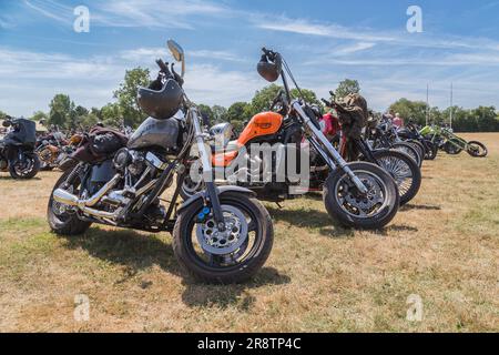 Una fila di motociclette potenti parcheggiate a un rally motociclistico. I caschi dei piloti sono appesi al manubrio. Foto Stock