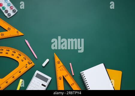 Composizione piatta con goniometro, triangolo e cancelleria su lavagna verde. Spazio per il testo Foto Stock