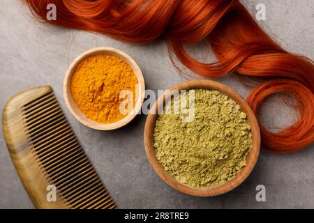 Composizione a posa piatta con henné e polvere di curcuma su tavolo grigio chiaro. Colorazione naturale dei capelli Foto Stock