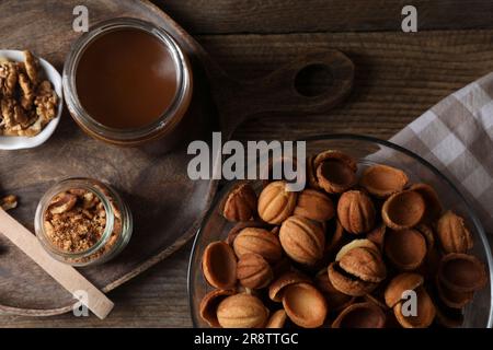 Preparare biscotti a forma di noce. Impasto cotto, latte condensato caramellato e noci su tavola di legno, piatto Foto Stock