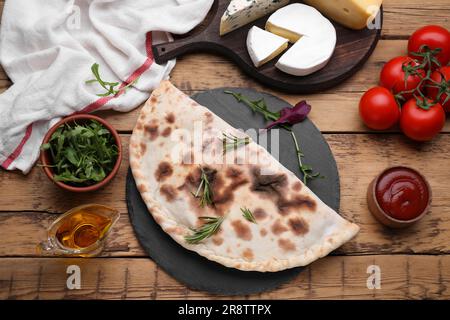 Delizioso calzone e prodotti su un tavolo in legno, piatto Foto Stock