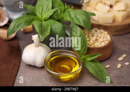 Ingredienti diversi per cucinare una gustosa salsa al pesto su un tavolo marrone ruvido, primo piano Foto Stock