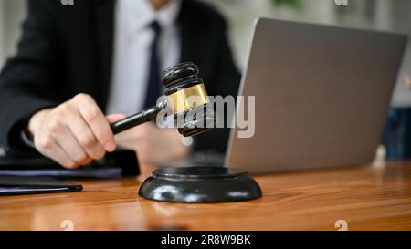 Immagine ravvicinata di un avvocato professionista che tiene un martelletto del giudice alla sua scrivania in aula. avvocato, avvocato, notaio, avvocato Foto Stock