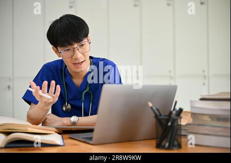 Un giovane studente o medico asiatico maschio intelligente e professionale sta avendo un incontro online con il suo team medico o un controllo medico online con Foto Stock