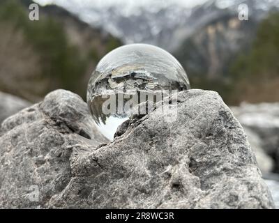 Lensball, sfera di cristallo sulle rocce, che riflette un torrente alpino, sullo sfondo la famosa montagna Zimba di Montafon (Vorarlberg, Austria). Foto Stock