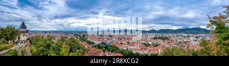 Paesaggio urbano della città vecchia di Graz e della Torre dell'Orologio (Grazer Uhrturm), famosa attrazione turistica di Steiermark, Austria, in un giorno nuvoloso Foto Stock