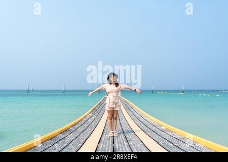 Allegra giovane donna asiatica in piedi sul pontile nel mare tropicale durante le vacanze estive Foto Stock