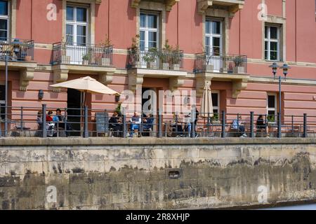 Berlino, Germania - 18 aprile 2023: Veduta delle persone sedute al ristorante all'aperto vicino al fiume Sprea a Berlino, Germania Foto Stock