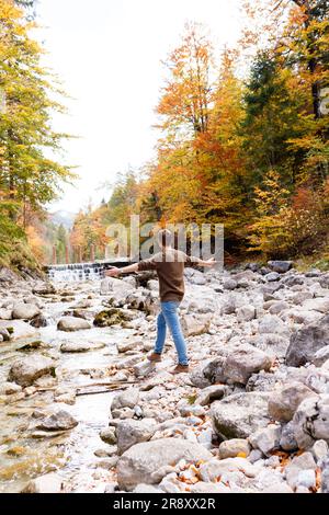 Uomo vicino a un fiume di montagna nelle foreste delle Alpi Foto Stock