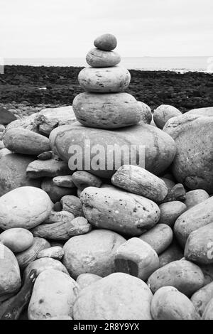 Piccola torre di pietre su una spiaggia con sfondo sfocato Foto Stock