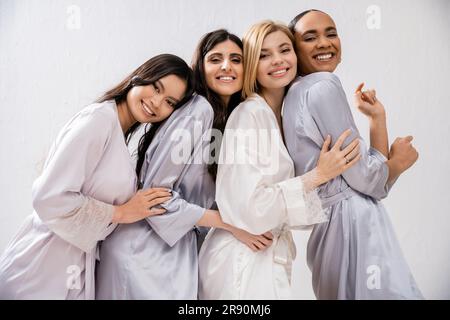 doccia nuziale, quattro donne, sposa felice e damigelle in abiti di seta, guardando la macchina fotografica, diversità culturale, divertirsi insieme, obiettivi di amicizia, br Foto Stock