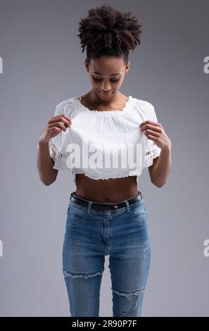 Mi sono macchiata? La giovane donna esamina la sua camicia per la pulizia, guardando in basso, indossando il vestito. Bella ragazza dalla pelle scura con capelli afro, indossata Foto Stock