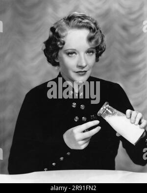 Hollywood, California: c. 1934 l'attrice della Fox Film Rosemary Ames usa una coppa per gli occhi piena di latte per calmare gli occhi dopo una faticosa giornata sul set. Foto Stock