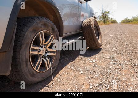 Un'auto 4x4 con pneumatico sgonfio ha la ruota di scorta pronta per sostituirla sulla Gibb River Road nell'Australia Occidentale Foto Stock