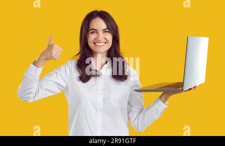 Donna felice soddisfatta che lavora in remoto utilizzando un notebook mostrando il gesto del pollice in alto. Foto Stock