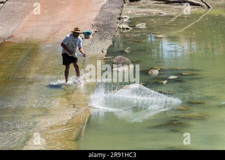 Un uomo getta una rete fishig nel fiume South Alligator a Cahils attraversando il territorio del Nord in Australia Foto Stock