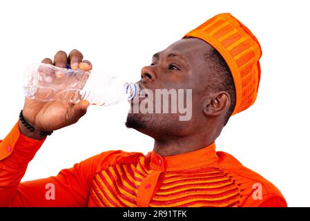 bel giovane uomo che indossa abiti arancioni che beve acqua minerale da una bottiglia di plastica. Foto Stock