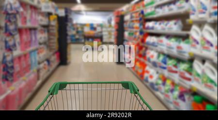 Un carrello della spesa è collocato al centro di una corsia di un supermercato piena di una serie di articoli di alimentari Foto Stock