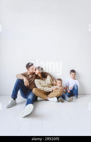 Famiglia con due bambini seduti al piano Foto Stock