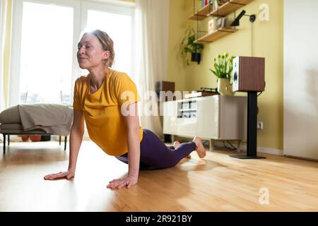 Giovane donna a praticare yoga a casa Foto Stock