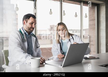 Colleghi medici che discutono sul portatile in ospedale Foto Stock