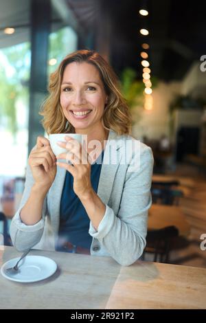 Donna d'affari sorridente che tiene la tazza al caffè Foto Stock